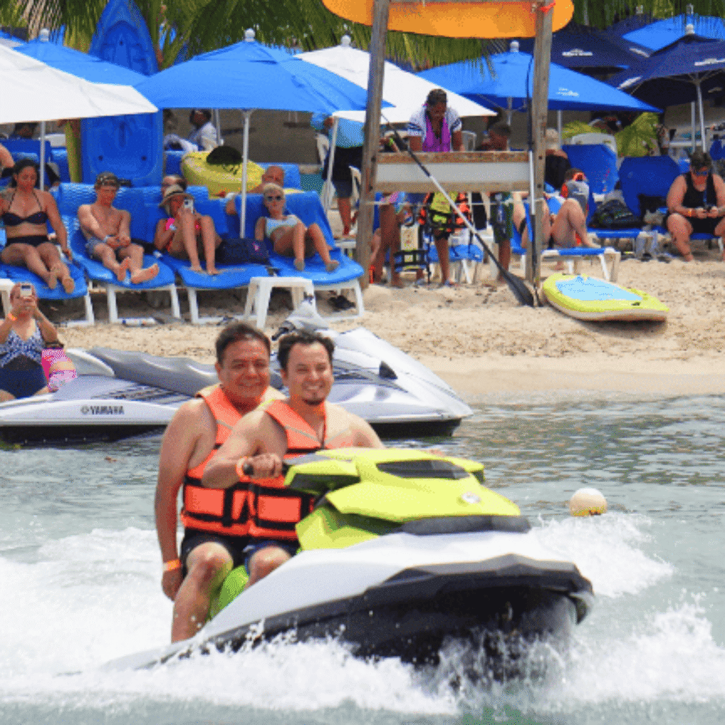 Cozumel jet ski rental prices for two people riding a jet ski away from the beach with dozens of vacationers shown on the beach