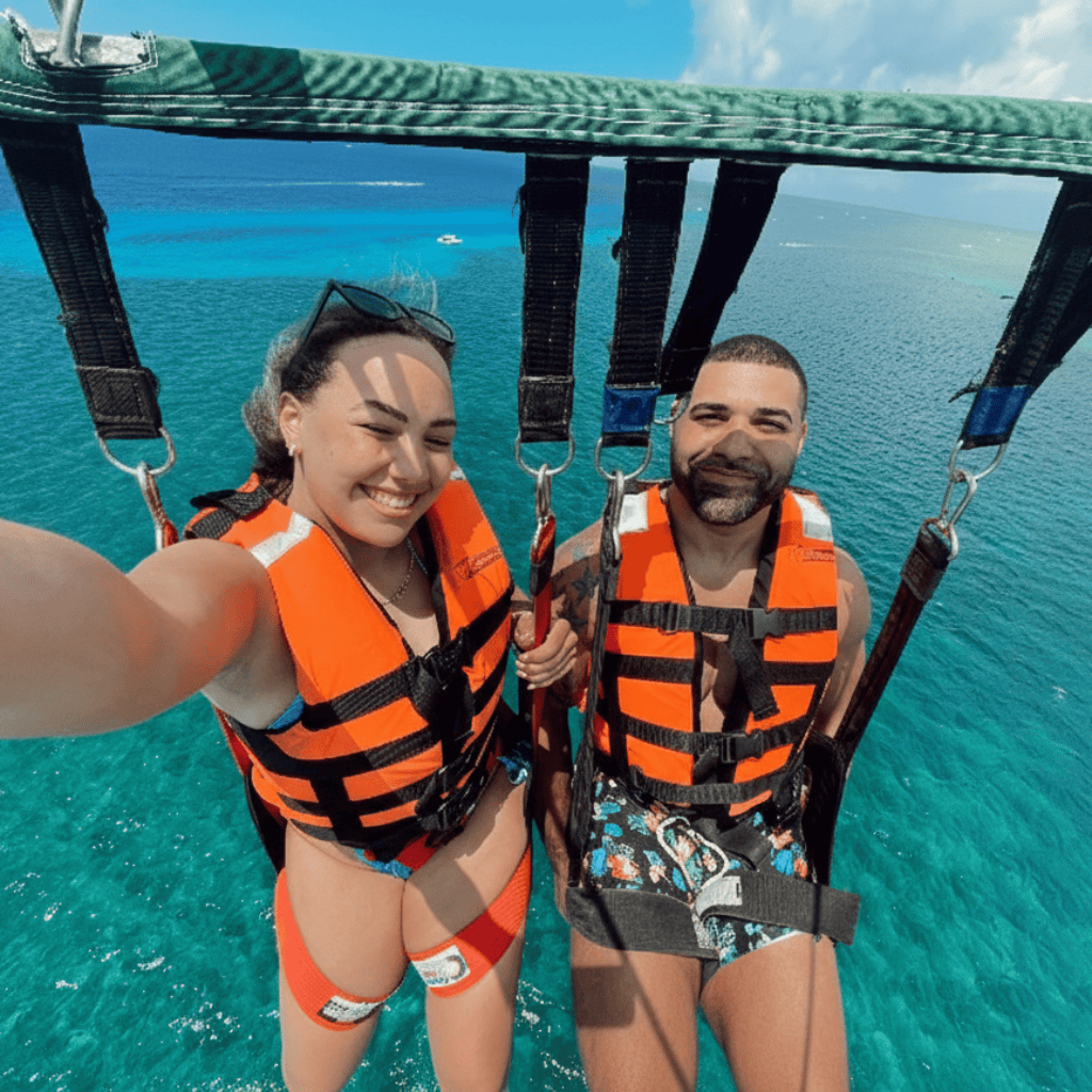 A couple Parasailing in Cozumel taking a selfie from high in the sky smiling