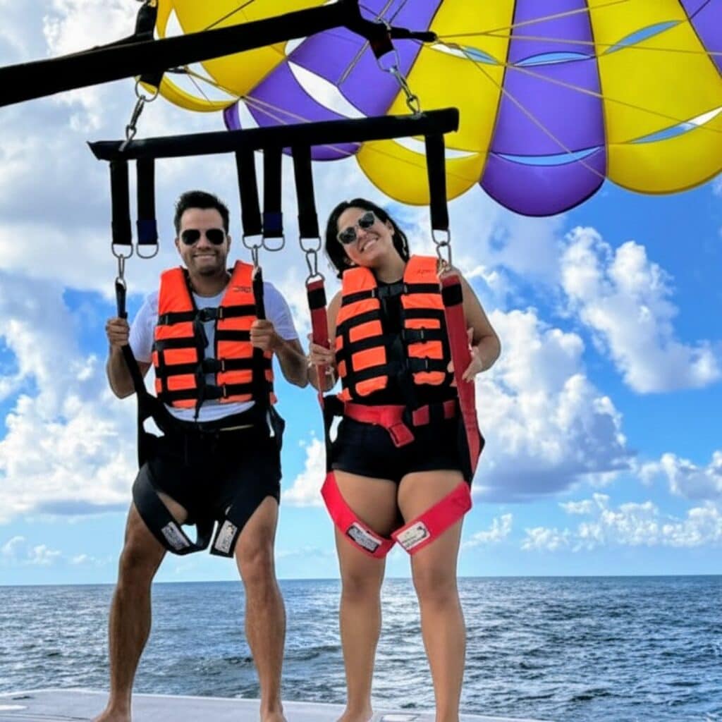 A couple standing on a rear board deck during a Parasail Cozumel tour with the ocean in the background