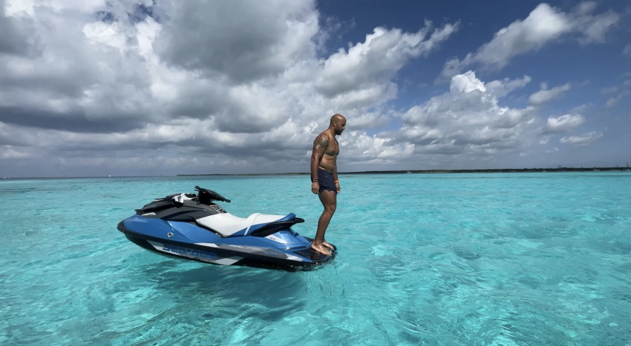 A man diving off the back of a blue jet ski into Crystal clear Cozumel water to snorkel